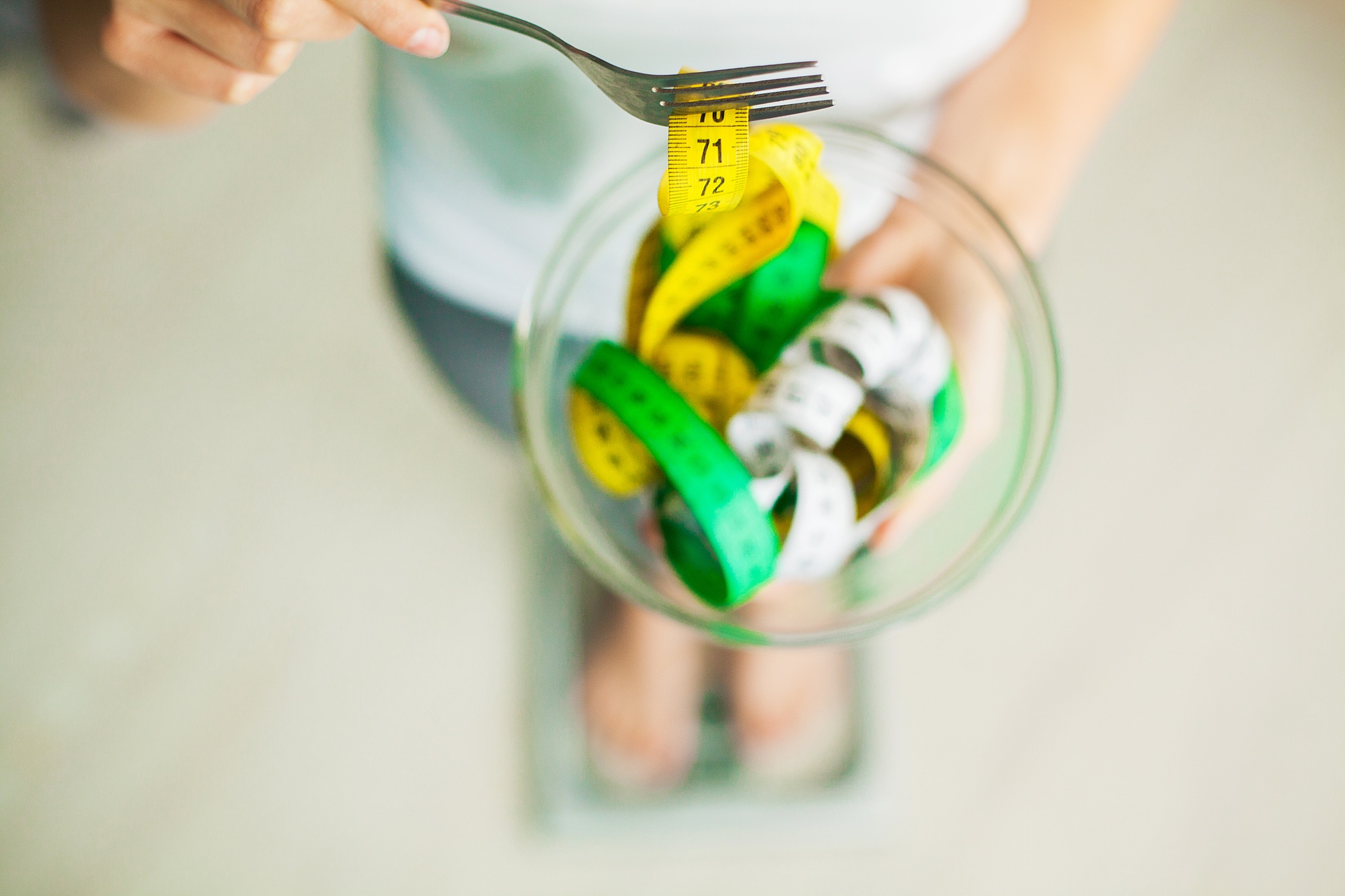Diet and Weight Loss. Woman holds bowl and fork with measuring tape